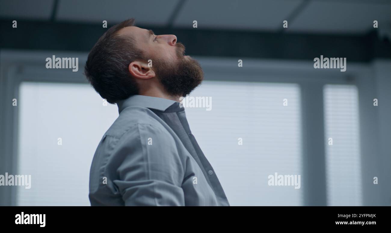 Nerveux et stressé employé de bureau respire fortement, s'assoit sur le sol après avoir détruit la salle de bureau. Homme d'affaires frustré après l'échec d'un accord commercial ou recevoir de mauvaises nouvelles. Crise financière. Épuisement du travail. Banque D'Images