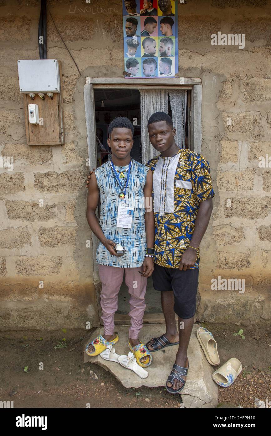 Jeunes hommes debout devant un salon de coiffure à Takpatchiomey, Couffo, Bénin Banque D'Images