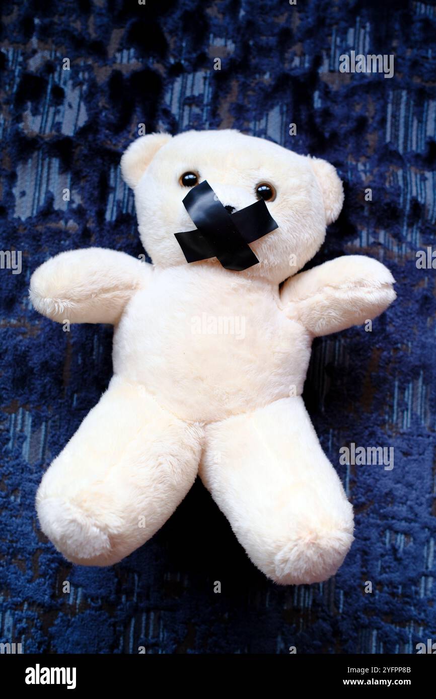 Ours en peluche avec du ruban adhésif sur sa bouche. Symbole du silence pendant la maltraitance des enfants Banque D'Images
