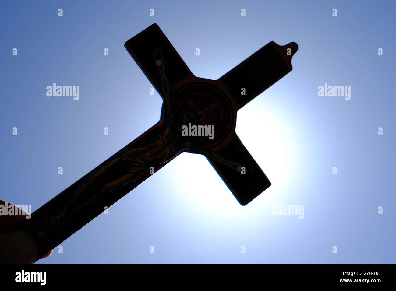 Homme priant avec une croix de bois contre le ciel bleu. Gros plan sur la main. Symbole du christianisme. Banque D'Images