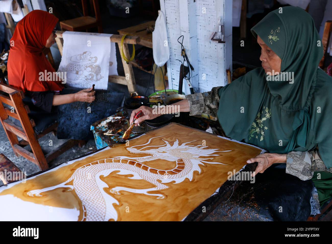 Production de batik. Femme utilisant de la cire chaude pour dessiner un dessin de dragon. Yogyakarta. Indonésie. Banque D'Images
