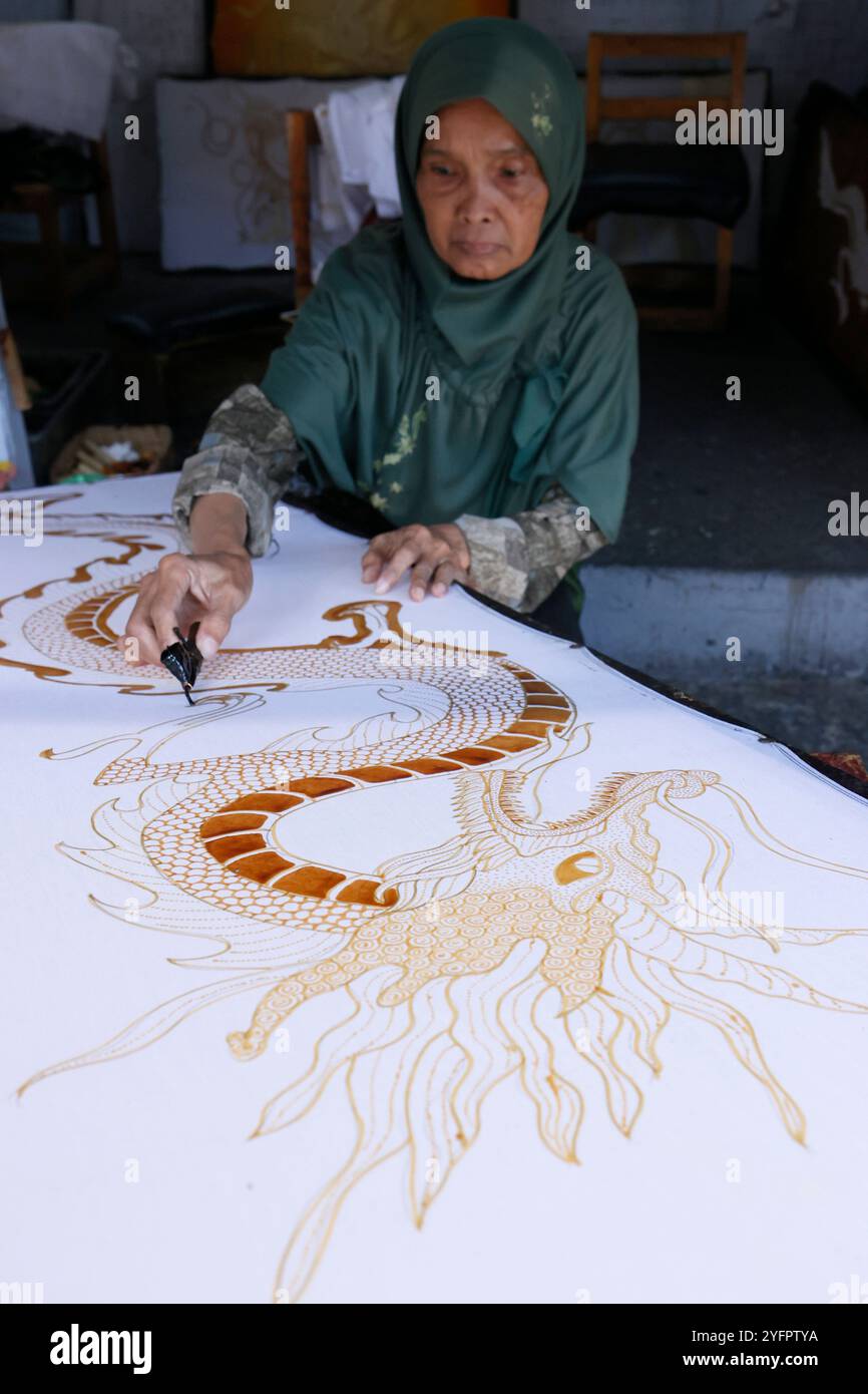 Production de batik. Femme utilisant de la cire chaude pour dessiner un dessin de dragon. Yogyakarta. Indonésie. Banque D'Images