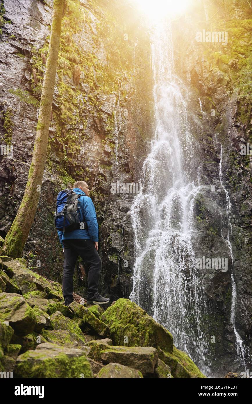 Attraction touristique de l'Allemagne, chutes de Burgbach Cascade près de Schapbach, Forêt Noire, Bade-Wurtemberg, Allemagne. Homme randonneur en veste bleue debout Banque D'Images