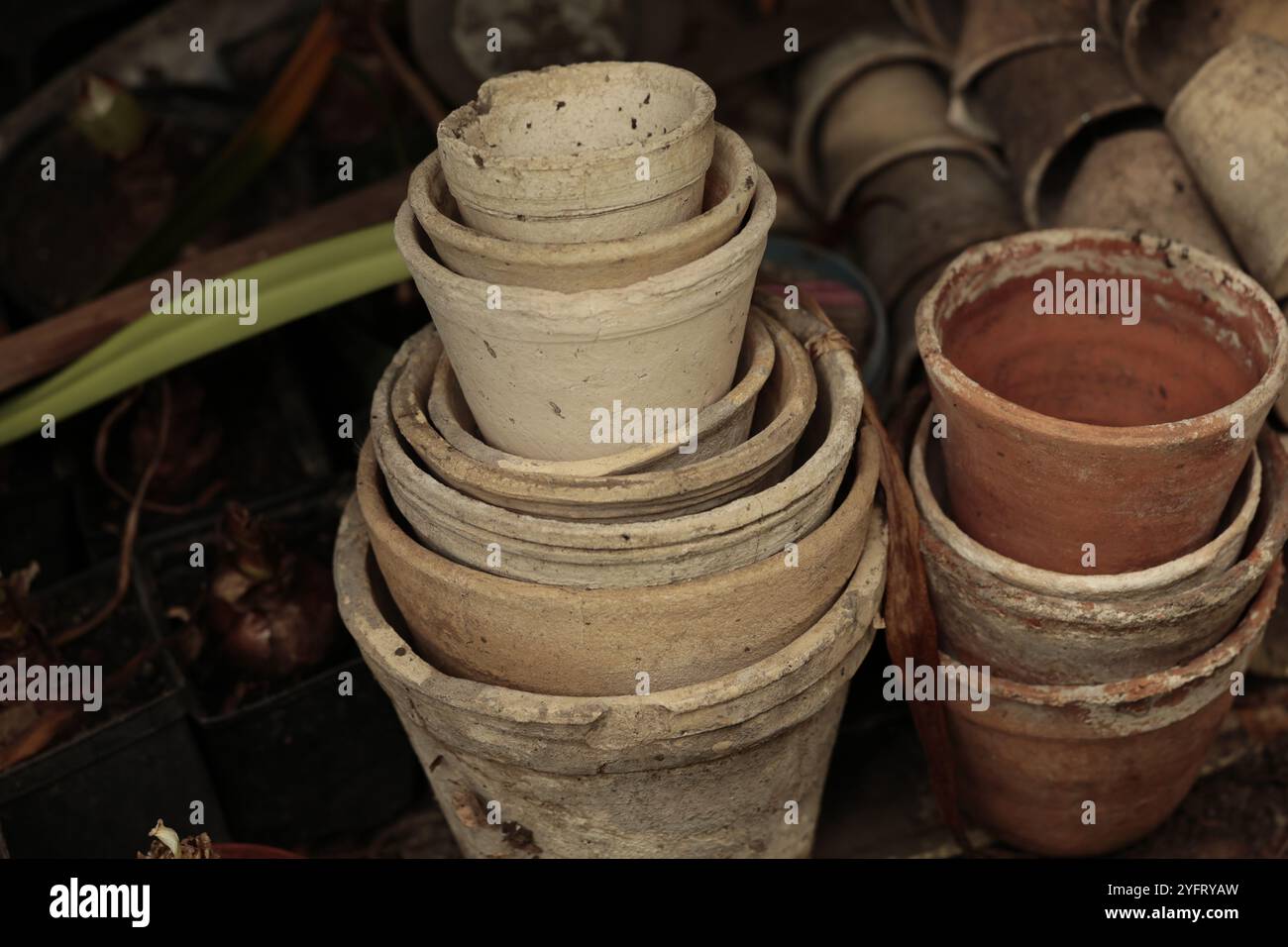 Gros plan des piles de vieux pots de fleurs en terre cuite usagés dans le hangar de jardinage Banque D'Images