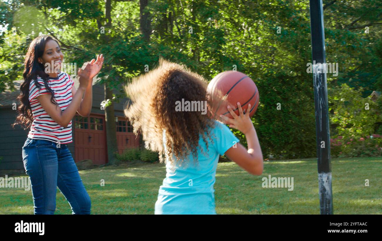 Mère et fille jouant au basket-ball à l'extérieur sur l'allée à la maison Banque D'Images