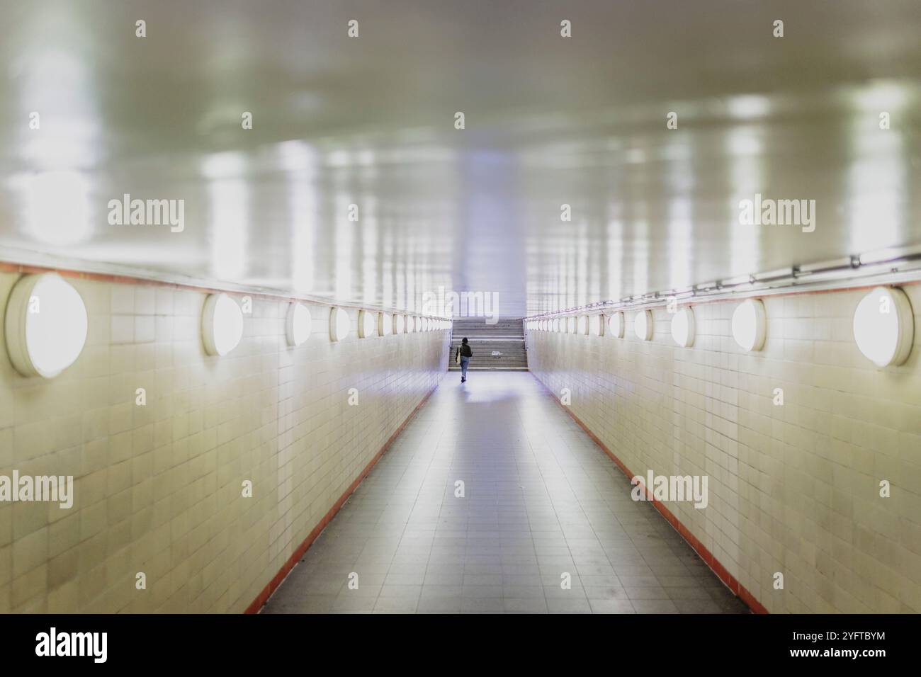 Une femme marche seule à travers un passage souterrain bien éclairé à la Nordbahnhof à Berlin, le 5 novembre 2024. Banque D'Images