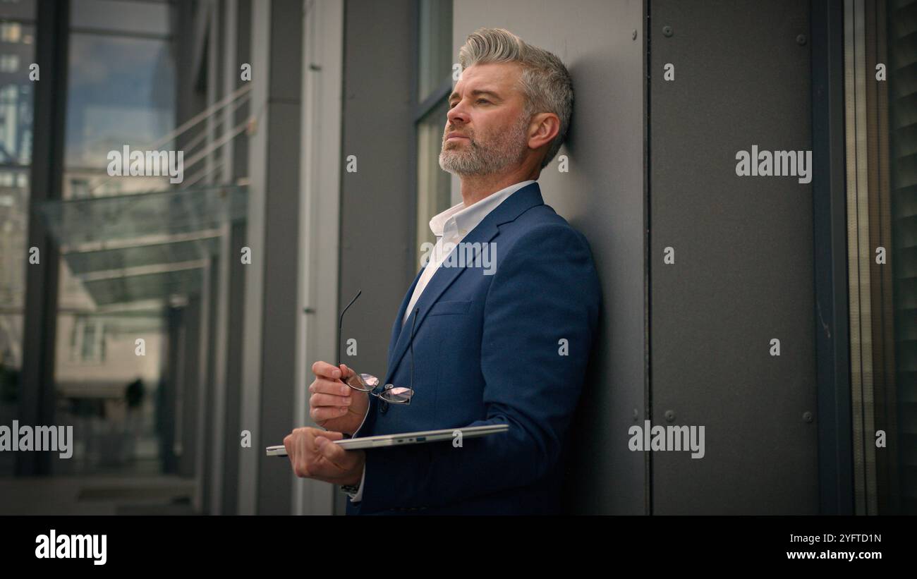 Fatigué épuisé vieux homme d'affaires caucasien vieux employeur mature homme d'affaires senior masculin d'âge moyen Manager avec ordinateur portable finir la ville de travail à l'extérieur Banque D'Images