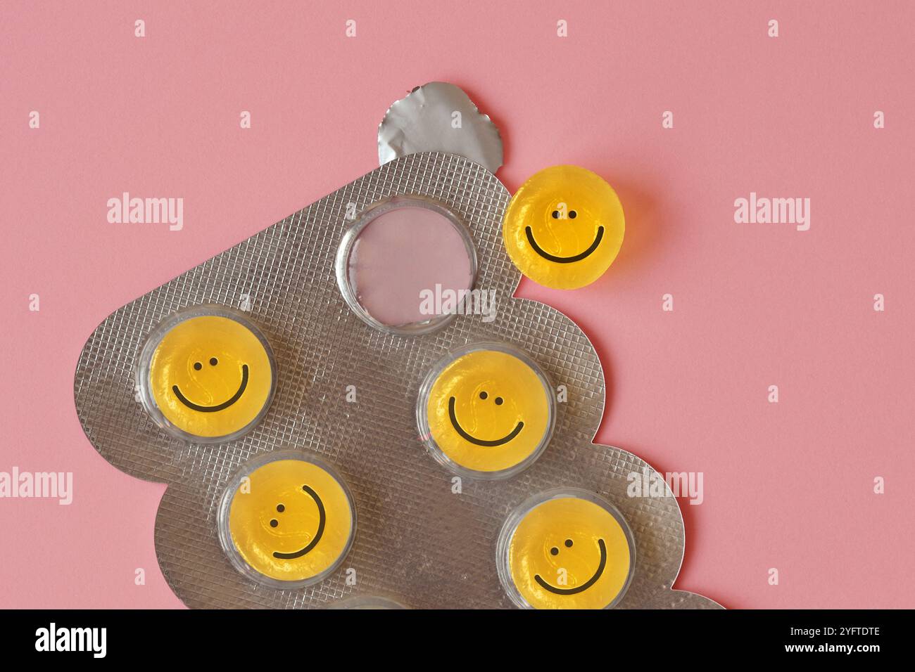 Gros plan de pilules avec des visages heureux dans des ampoules sur fond rose - concept de bonheur et de médecine Banque D'Images