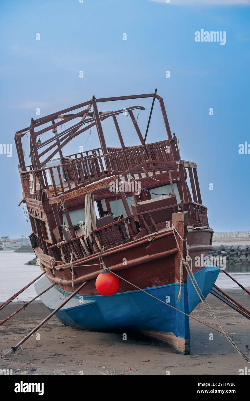 Un bateau en bois vieilli reposant sur Seeb Beach, Muscat, Oman. Banque D'Images