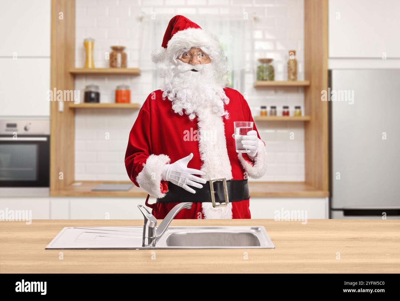 Père noël buvant un verre d'eau du robinet dans la cuisine Banque D'Images