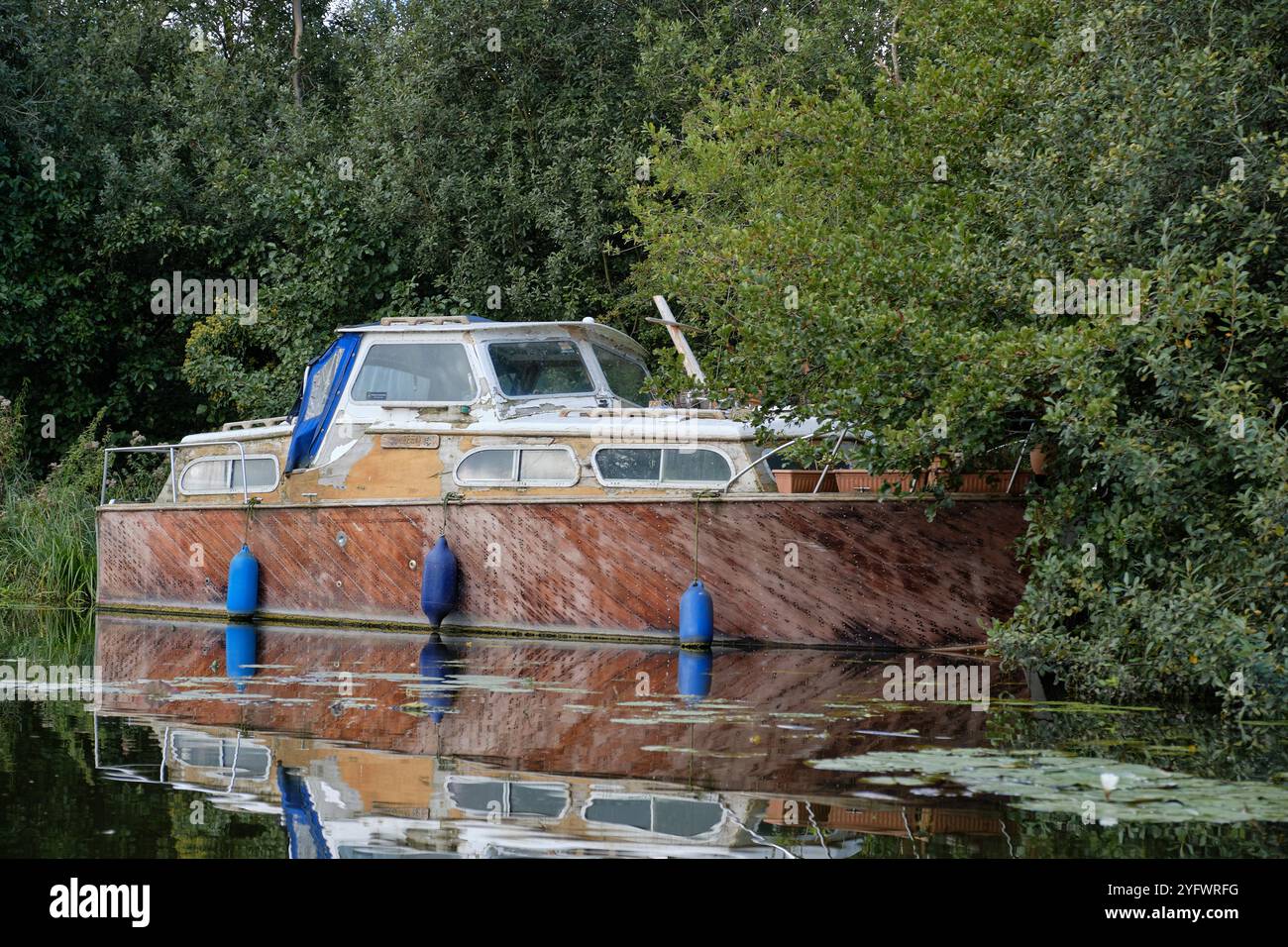 Un vieux bateau fluvial désaffecté est amarré sur le côté de Barton Broad, sur les Norfolk Broads, East Anglia. Cet engin en décomposition était autrefois une charmante péniche. Banque D'Images