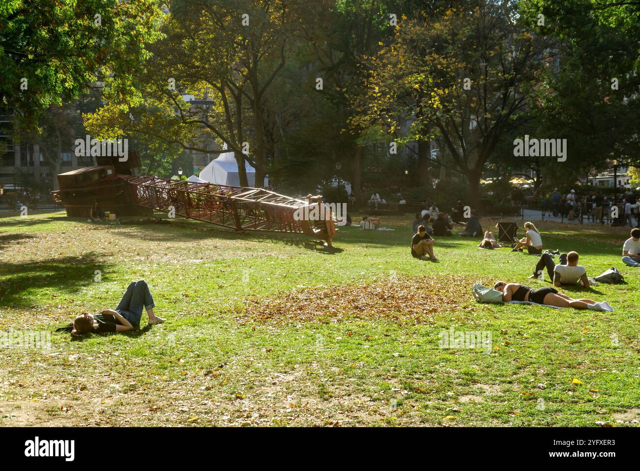 Les visiteurs du Madison Square Park profitent des bains de soleil par temps chaud inhabituels à côté de la « grue fixe » de Nicole Eisenman, sur la pelouse ovale, vue le jeudi 31 octobre 2024. Les températures pour les festivités d'Halloween ont atteint dans les années 70 supérieures (© Richard B. Levine) Banque D'Images