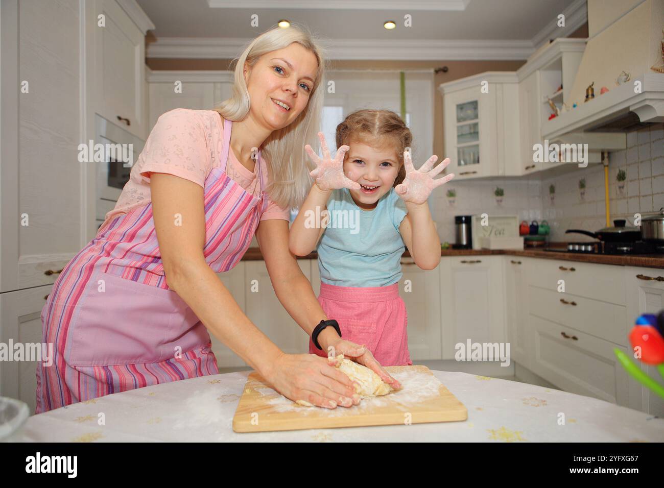 une mère et sa fille comme ils cuisinent ensemble dans une cuisine confortable. ils partagent des sourires et des rires, créant non seulement un repas, mais des souvenirs précieux Banque D'Images