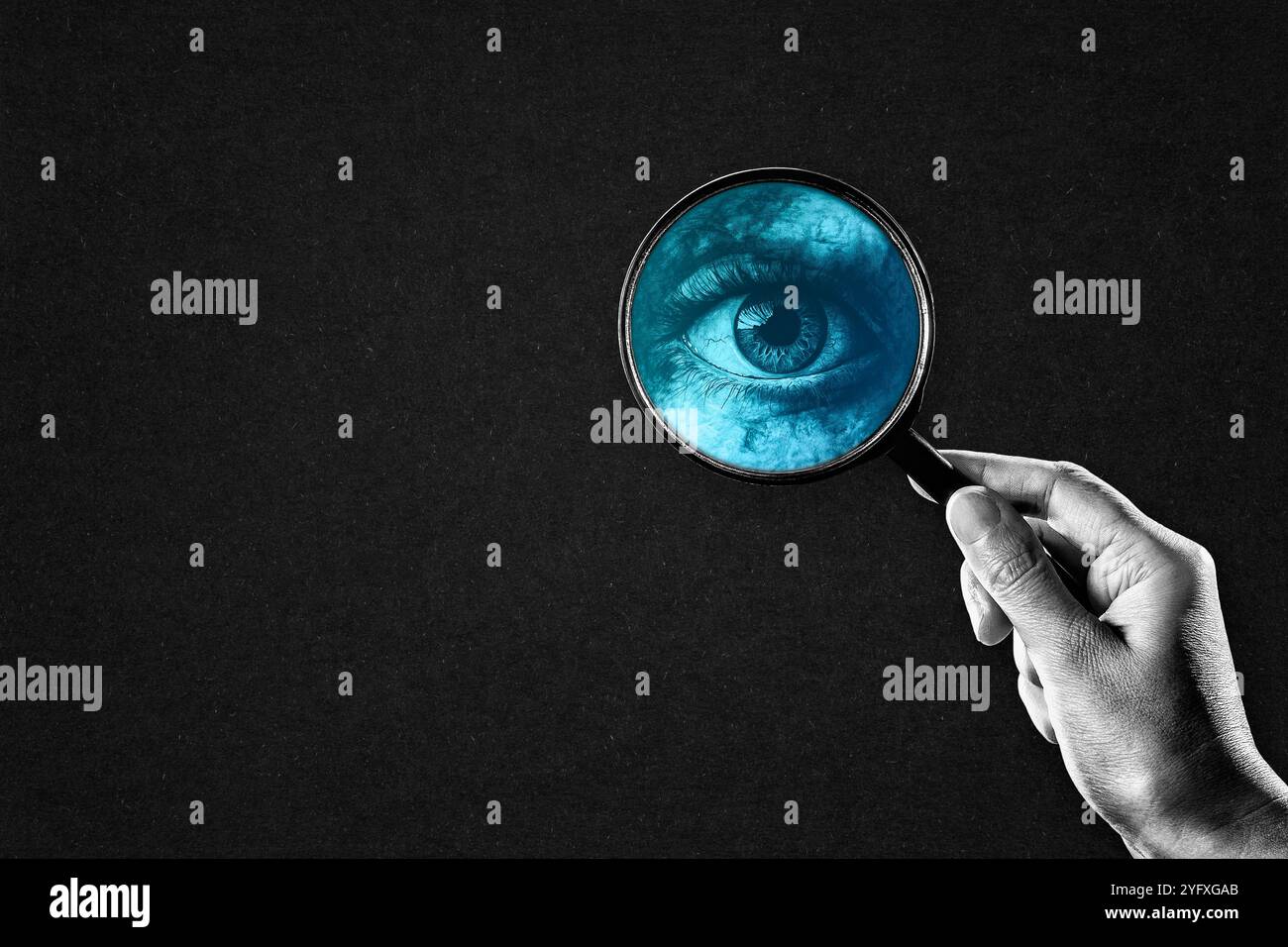 Main tenant la loupe avec yeux bleus en noir et blanc, Copier l'espace Banque D'Images