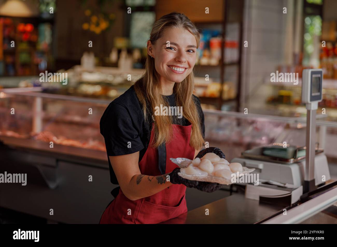 Un poissonnier souriant qui tient des fruits de mer frais dans une atmosphère de marché animée Banque D'Images