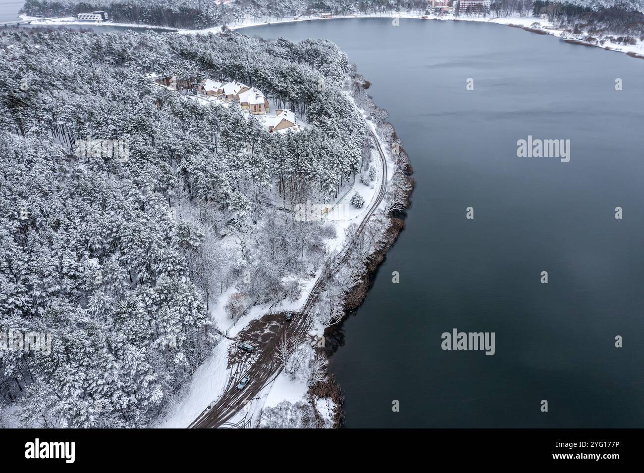 paysage enneigé hivernal. rive avec route de campagne et maisons dans la forêt enneigée. vue aérienne. Banque D'Images