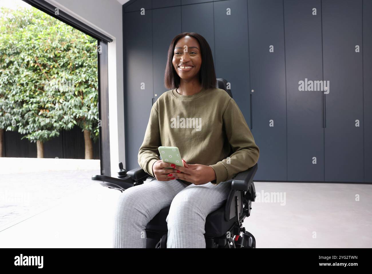 Femme assise en fauteuil roulant et tenant un téléphone intelligent Banque D'Images