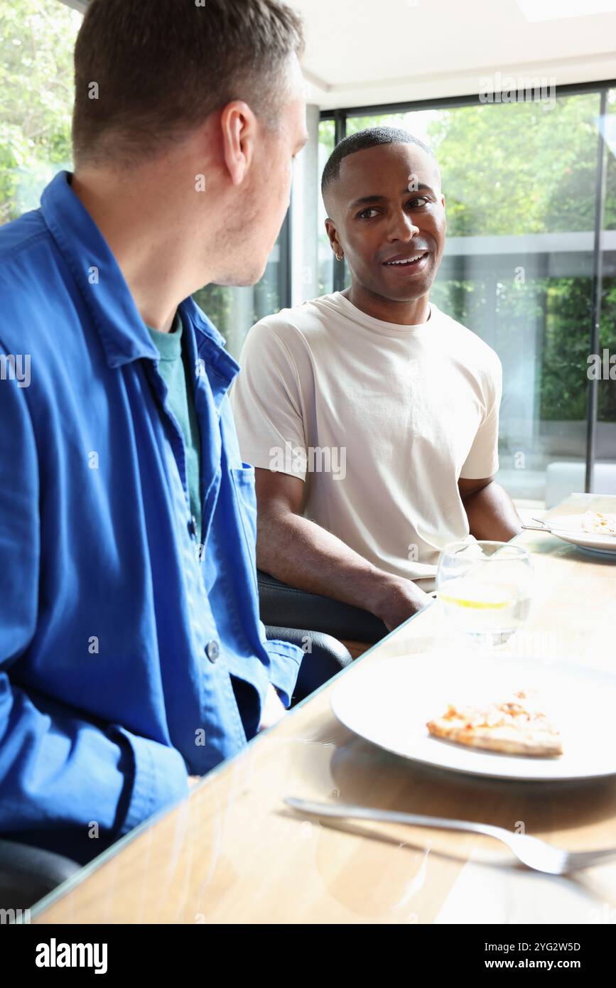 Des hommes souriants assis à table Banque D'Images