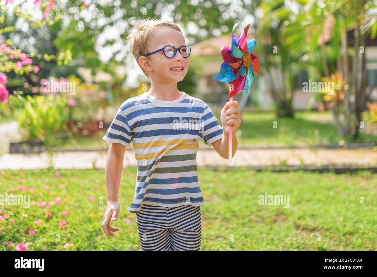 Garçon dans les lunettes joue avec la roue à épingles dans un jardin Banque D'Images