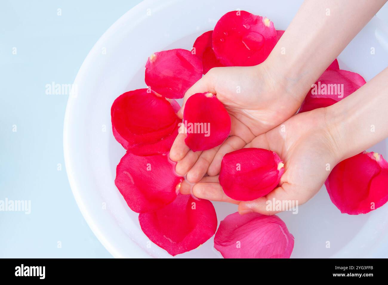 Main de femme dessinant de l'eau avec des pétales Banque D'Images