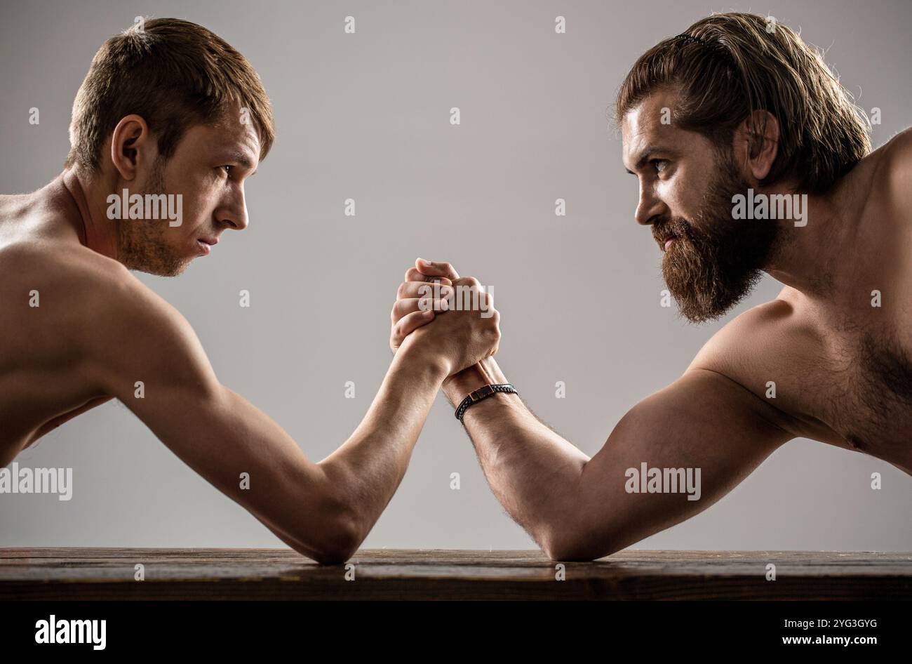 Deux mains d'homme ont un bras de lutte, forte et faible, match inégal. Homme barbu fortement musclé bras luttant un homme faible et puny Banque D'Images