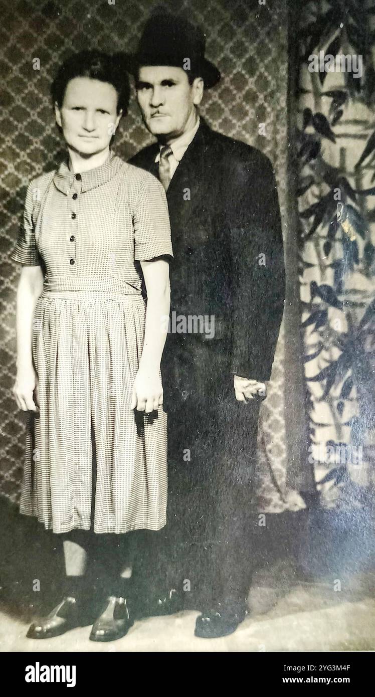 Novi Sad, Yougoslavie - années 1930 : photo vintage d'un couple marié posant devant des draperies colorées Banque D'Images