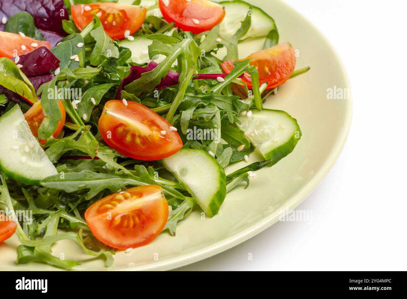 Salade avec tomates fraîches, concombre, roquette, basilic, épinards et sésame dans l'assiette. Repas de régime végétal sain. Gros plan. Banque D'Images