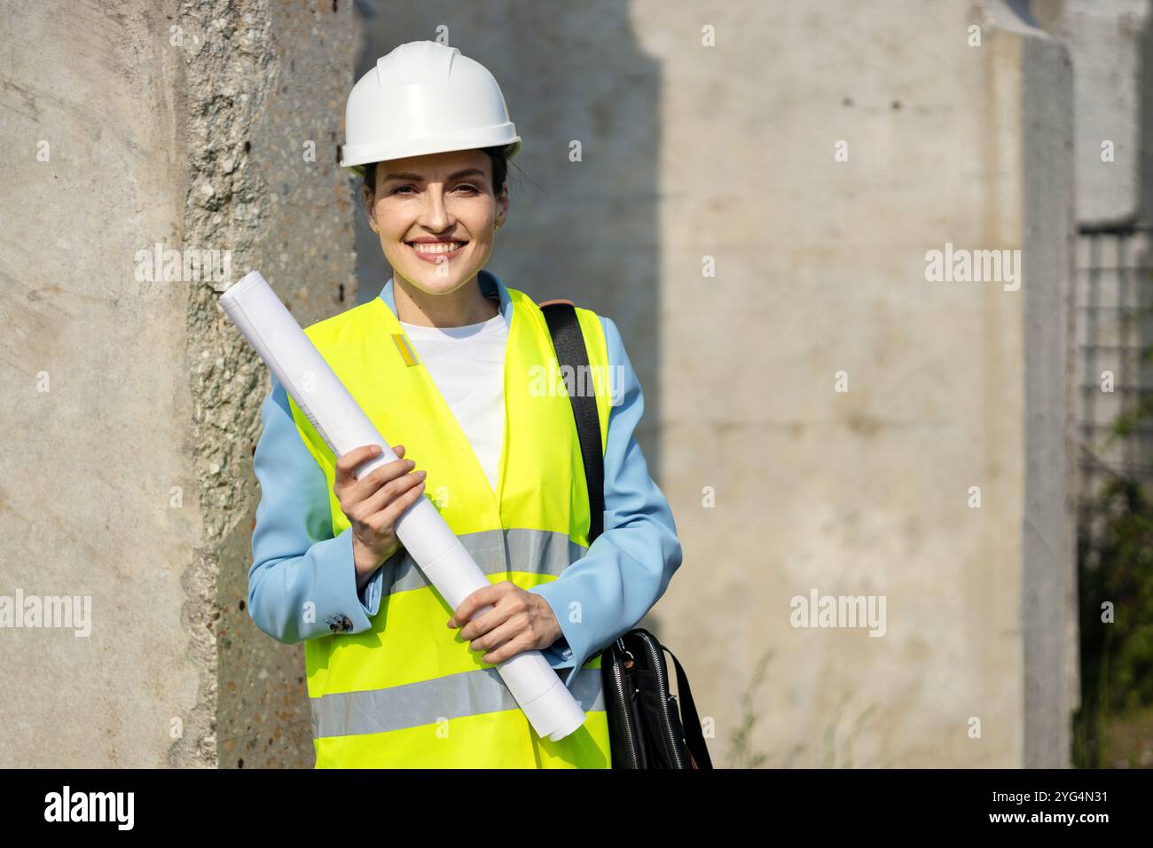 Portrait d’une heureuse architecte tenant des plans sur un chantier de construction, sur son premier grand projet. Copier l'espace Banque D'Images