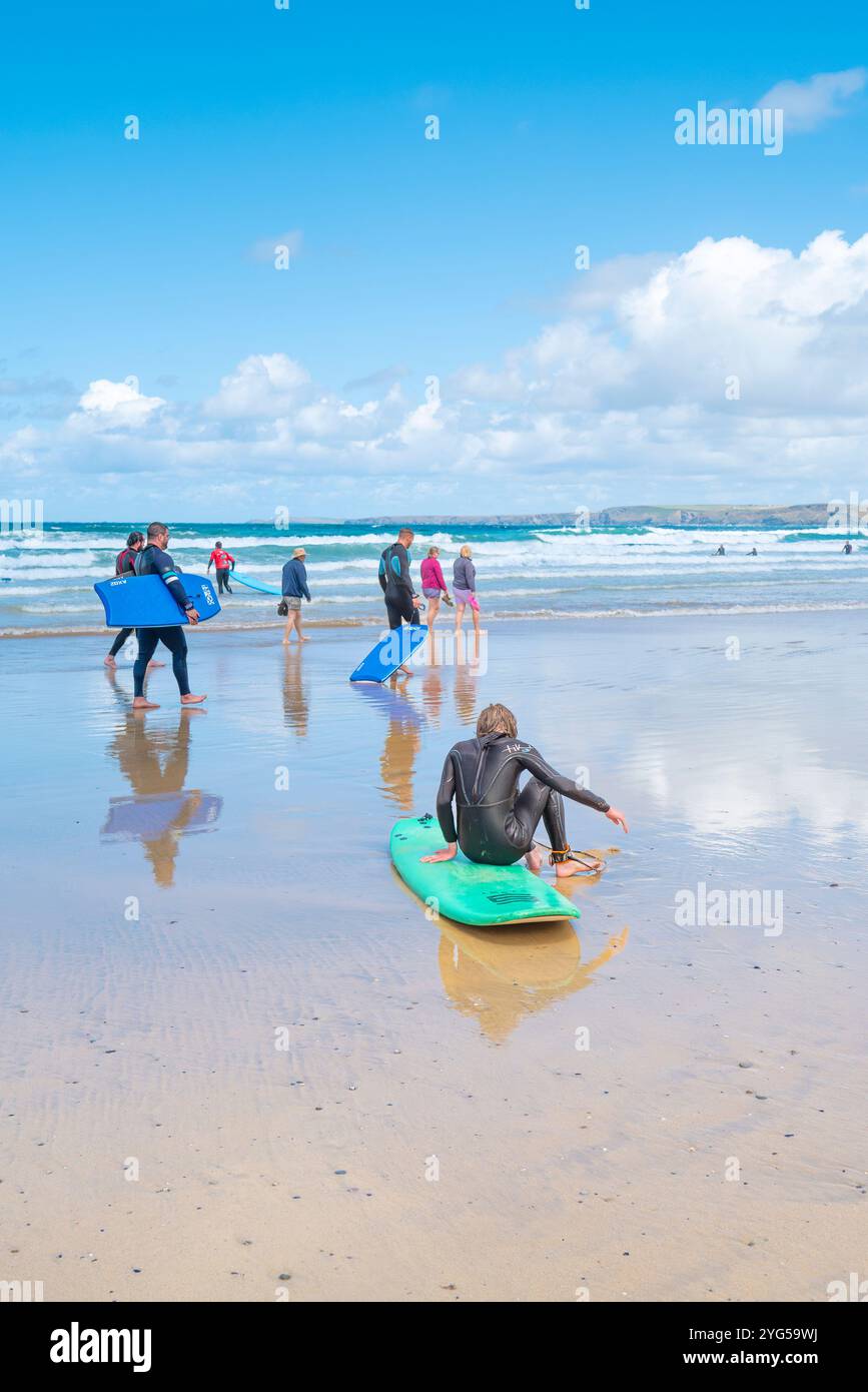 Un surfeur fatigué prenant une pause de surf assis sur sa planche de surf sur Towan Beach à Newquay en Cornouailles au Royaume-Uni. Banque D'Images