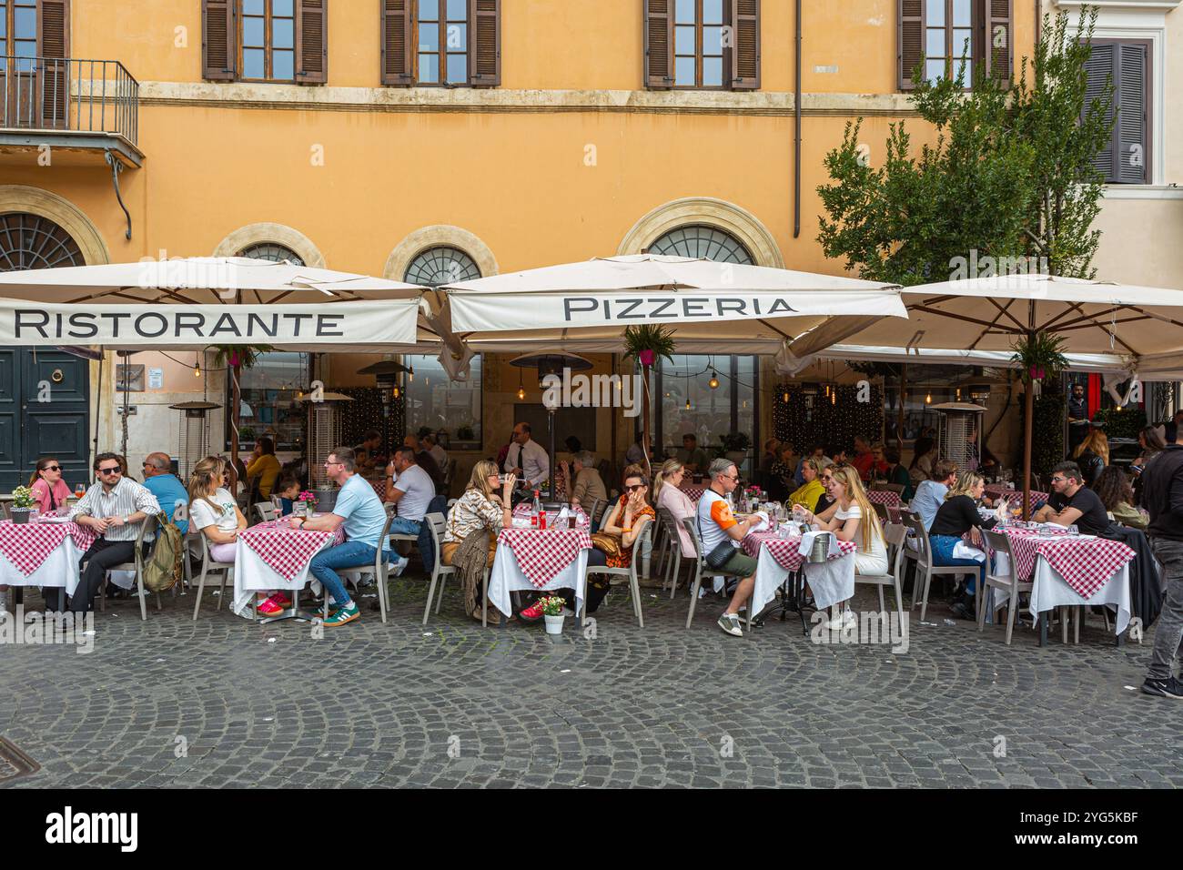 Touristes assis à des tables devant un restaurant sur la Piazza Navona à Rome Banque D'Images