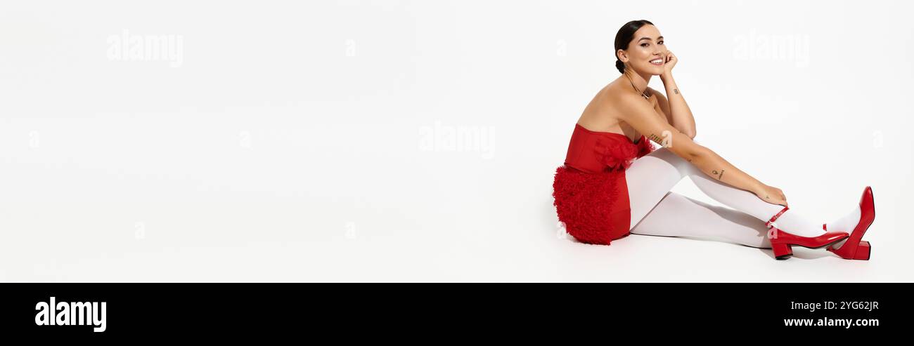 Une femme confiante en rouge pose élégamment, mettant en valeur sa tenue élégante et son calme. Banque D'Images