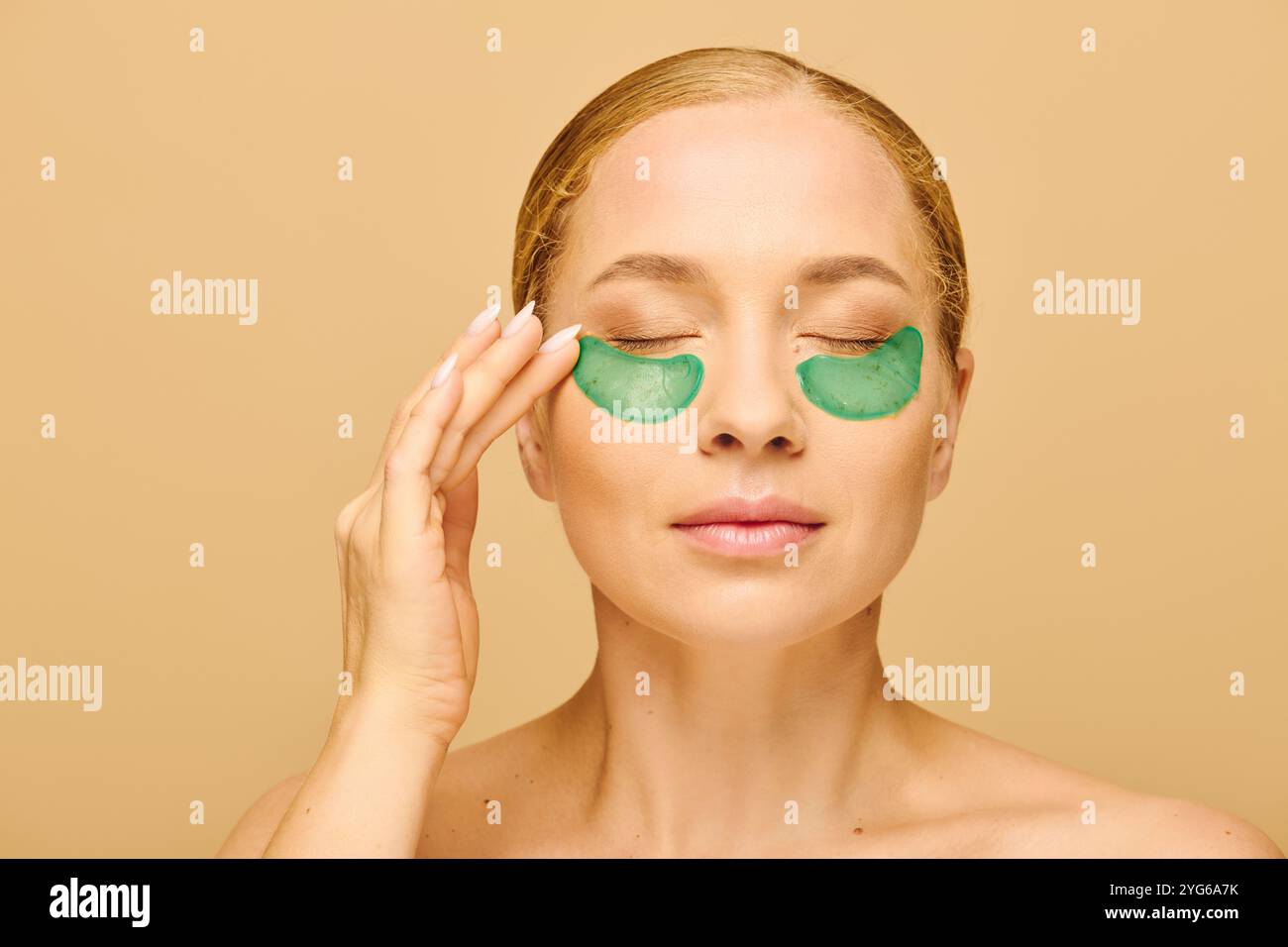 Une jeune femme de grande taille aime prendre soin de soi, en appliquant des taches vertes sous ses yeux. Banque D'Images