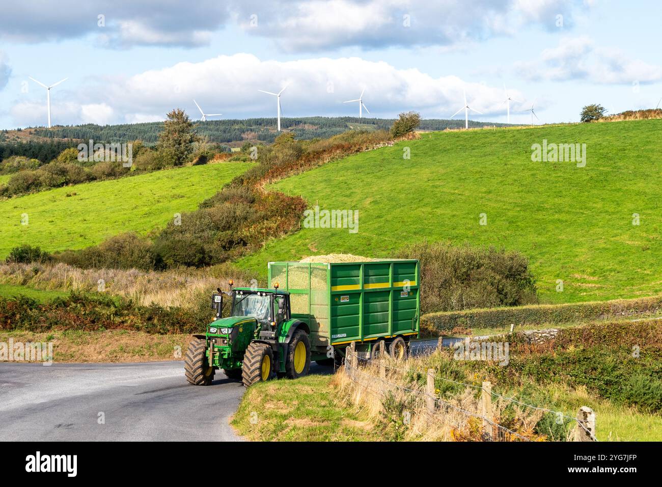 John Deere Tractor transporte du maïs fraîchement tiré dans la cour du fermier à Bauravilla, West Cork, Irlande. Banque D'Images