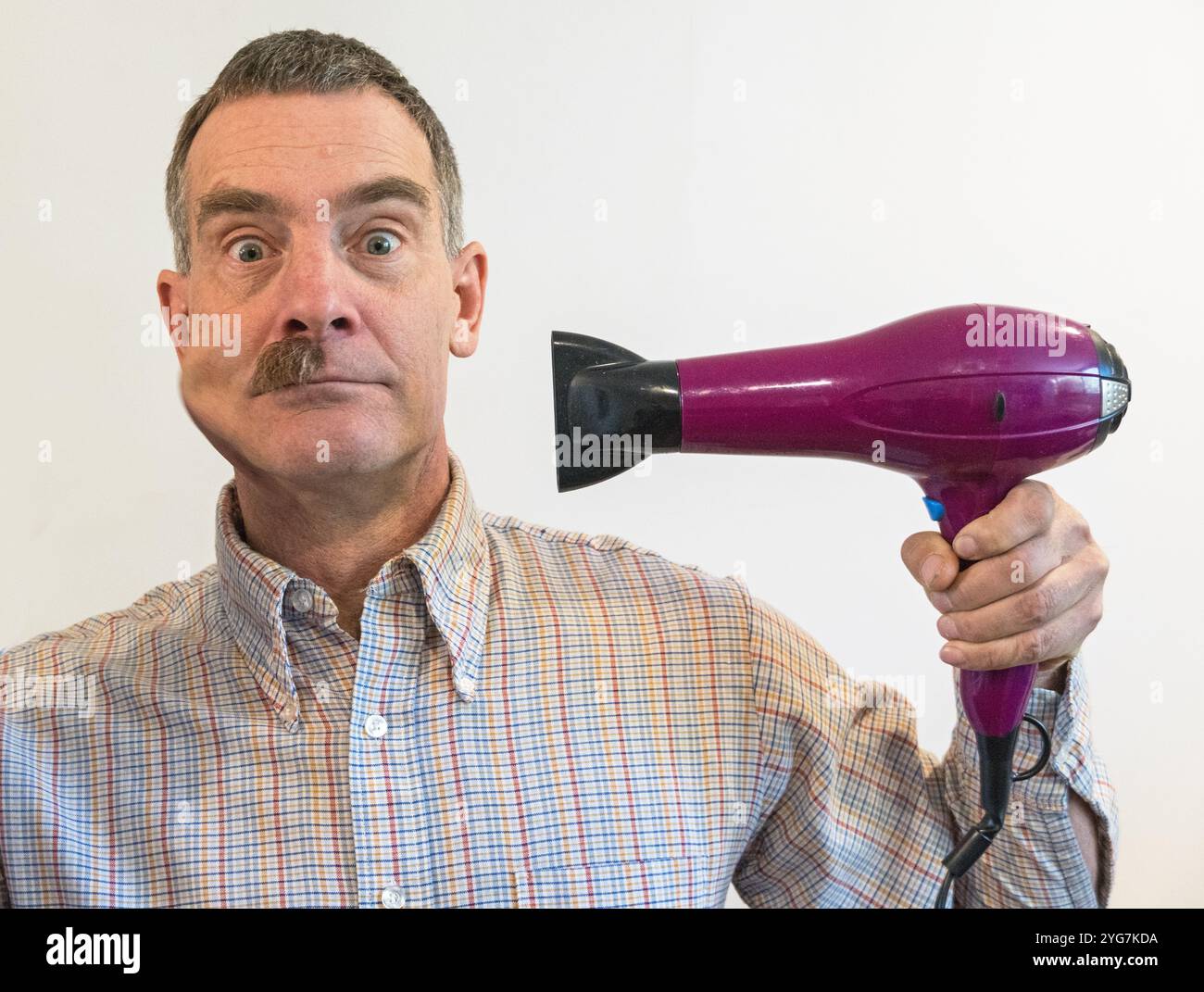homme soufflant sa moustache sur le côté avec un sèche-cheveux électrique Banque D'Images