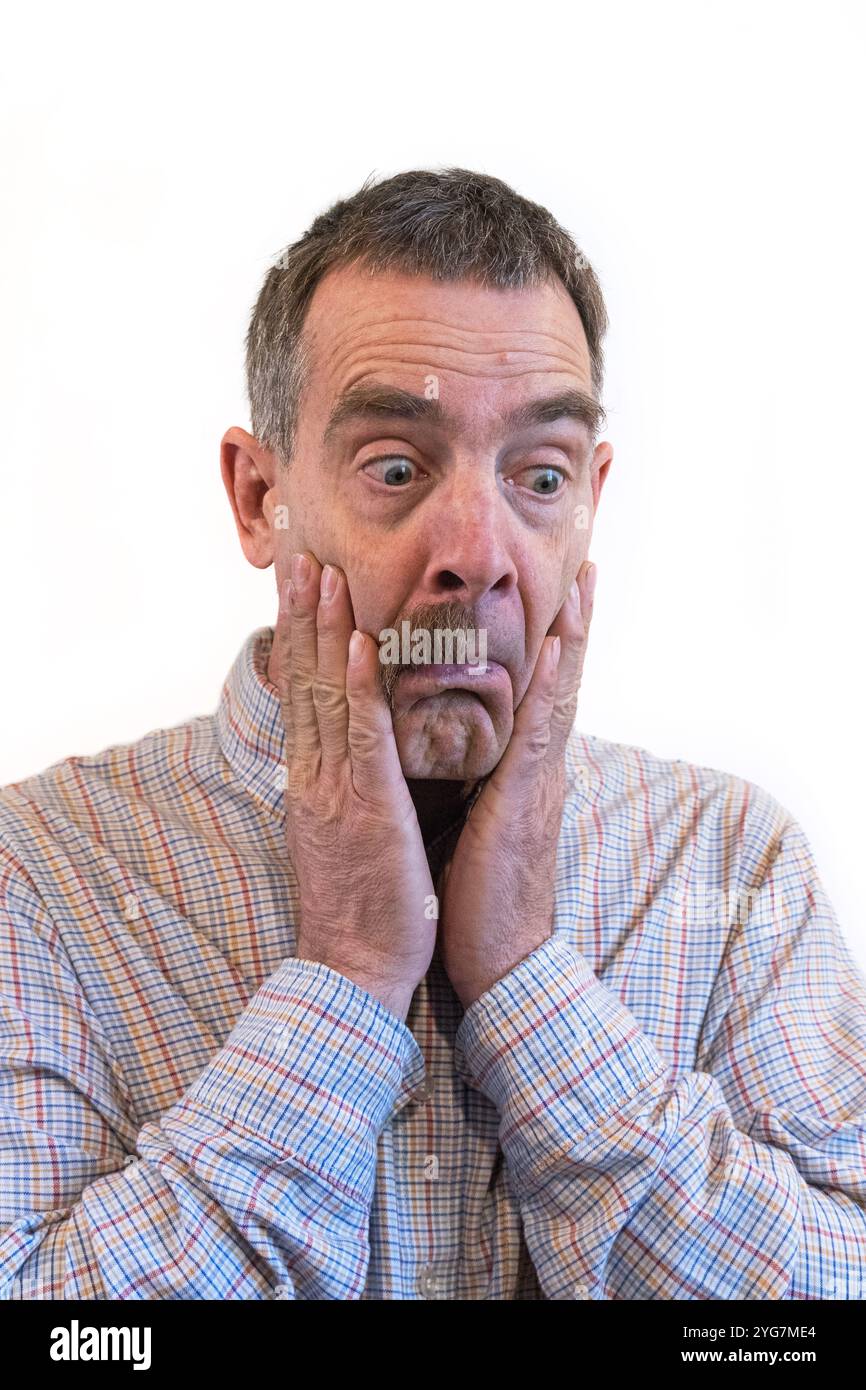 l'homme blanc d'âge moyen tient ses joues et regarde avec étonnement sa moustache à moitié manquante Banque D'Images