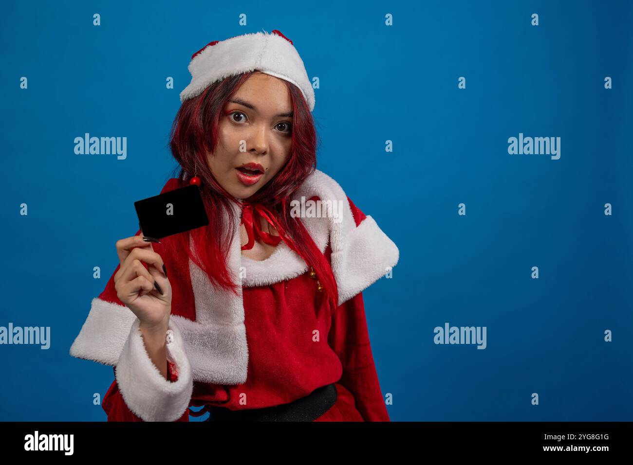 Une femme dans une tenue de père noël rouge tenant une carte noire Banque D'Images