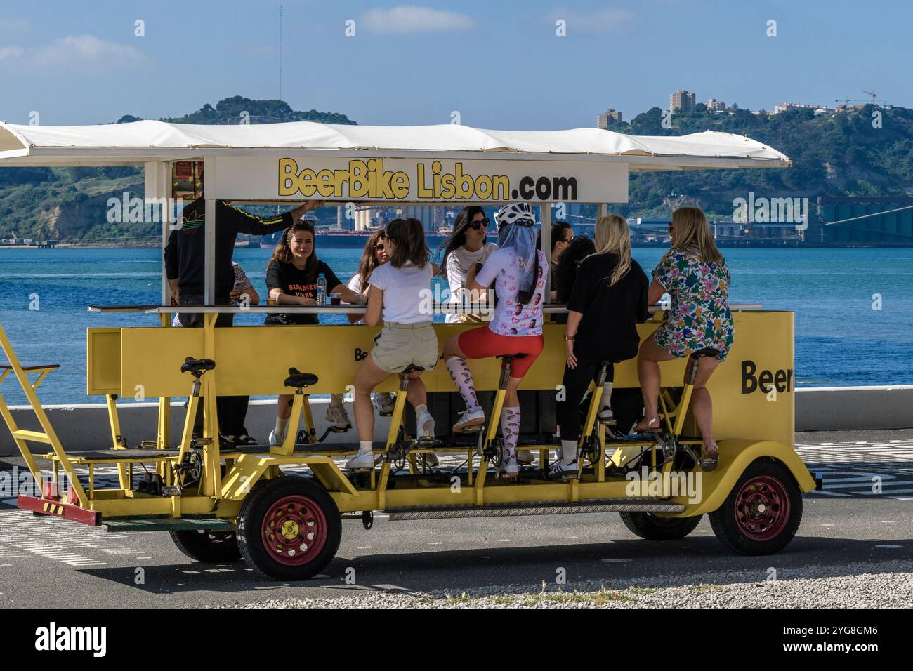Femmes assises au comptoir du bar d'un vélo de bière drôle sur la promenade de l'estuaire du Tage dans la ville de Lisbonne, capitale du Portugal, Europe. Banque D'Images