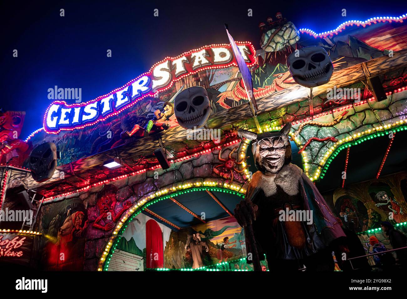 Soest, Allemagne. 06 novembre 2024. Une figure effrayante se tient devant un train fantôme à la Foire de tous les Saints. Selon les organisateurs, le festival traditionnel est la plus grande foire funiculaire du centre-ville en Europe. Environ un million de visiteurs sont attendus à la foire au milieu de la vieille ville historique de Soest jusqu'à dimanche. Crédit : Fabian Strauch/dpa/Alamy Live News Banque D'Images