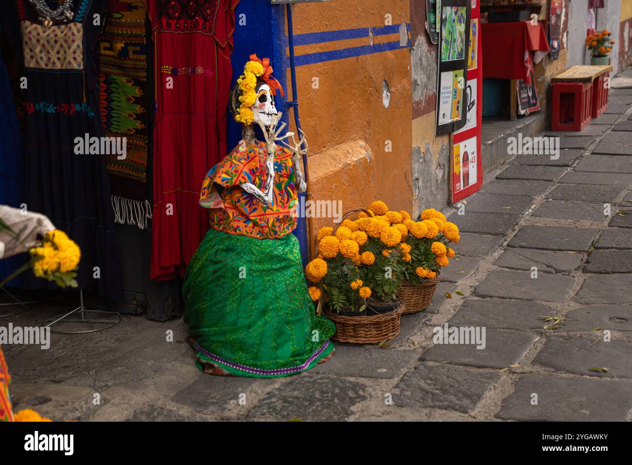 Figurine squelette habillée en tenue mexicaine traditionnelle, ornée de soucis, devant une boutique à San Angel pour le jour des morts (Día de los Muertos) Banque D'Images