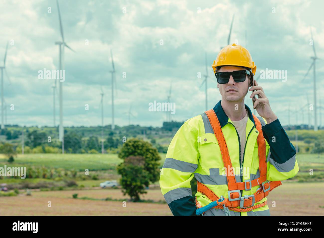 Technicien ingénieur téléphone appelant au service de travail des turbines éoliennes au champ de ferme de générateur d'électricité éolienne. Banque D'Images