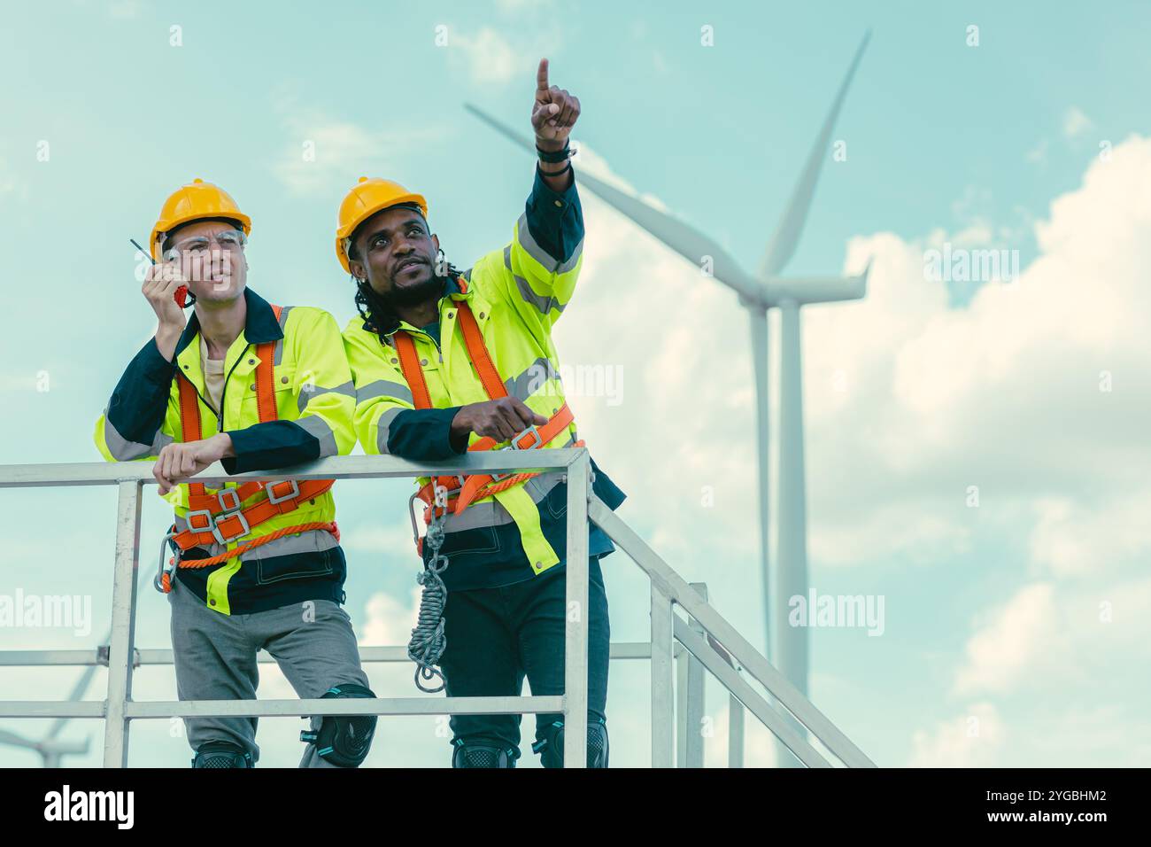L'équipe de technicien d'ingénieur mélange les travailleurs masculins debout à éoliennes travaillant le service au sous-sol de la ferme de générateur d'électricité éolienne. Banque D'Images