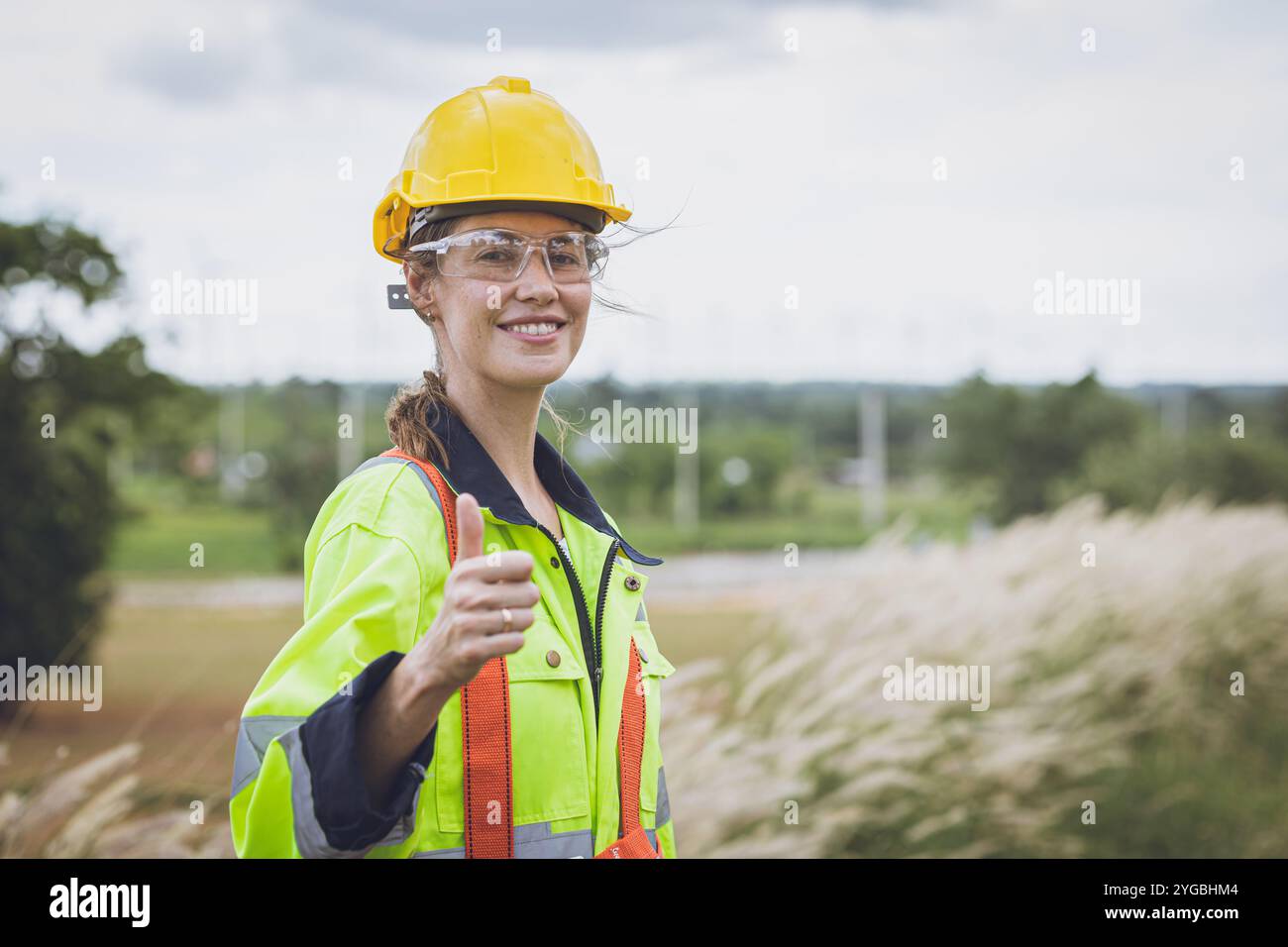 Portrait Thumbs Up femmes ingénieures adultes intelligentes bras debout souriant heureux croisé à Wind turbines Clean Power Generator Field fond. Banque D'Images