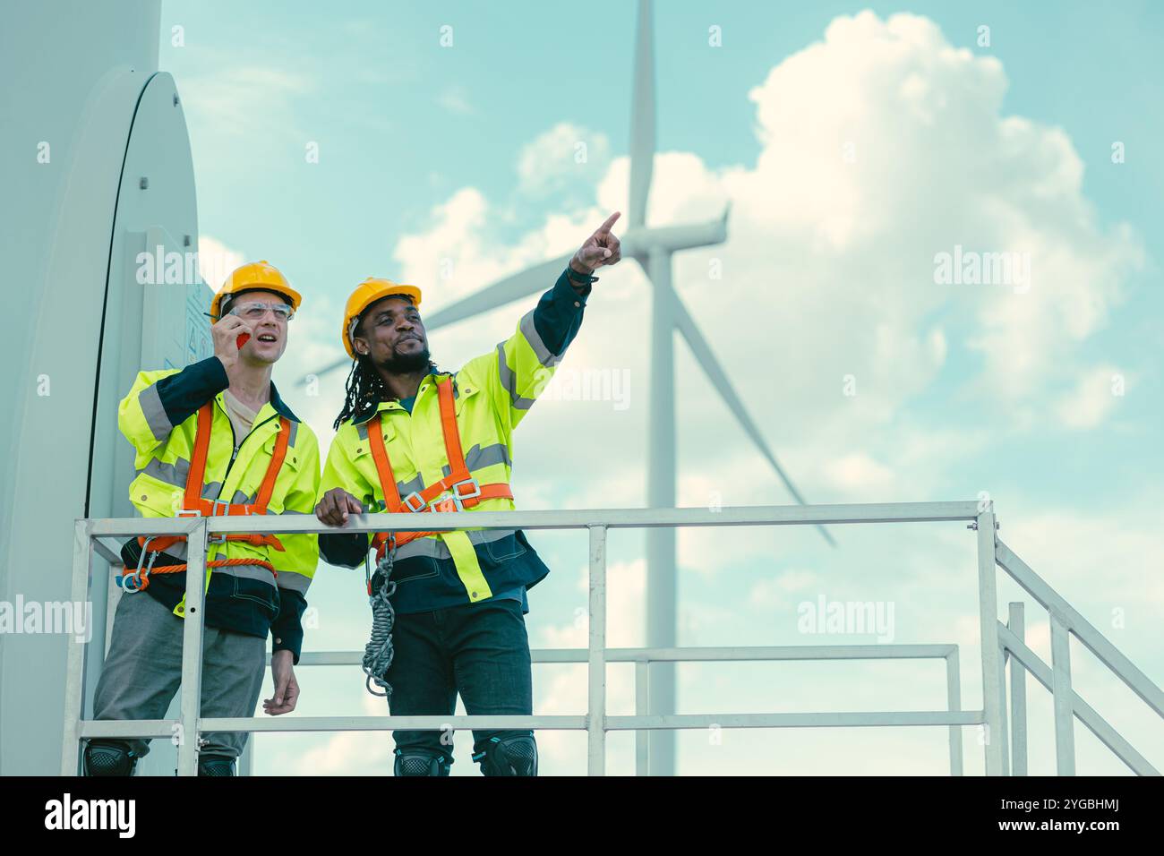 L'équipe de technicien d'ingénieur mélange les travailleurs masculins debout à éoliennes travaillant le service au sous-sol de la ferme de générateur d'électricité éolienne. Banque D'Images