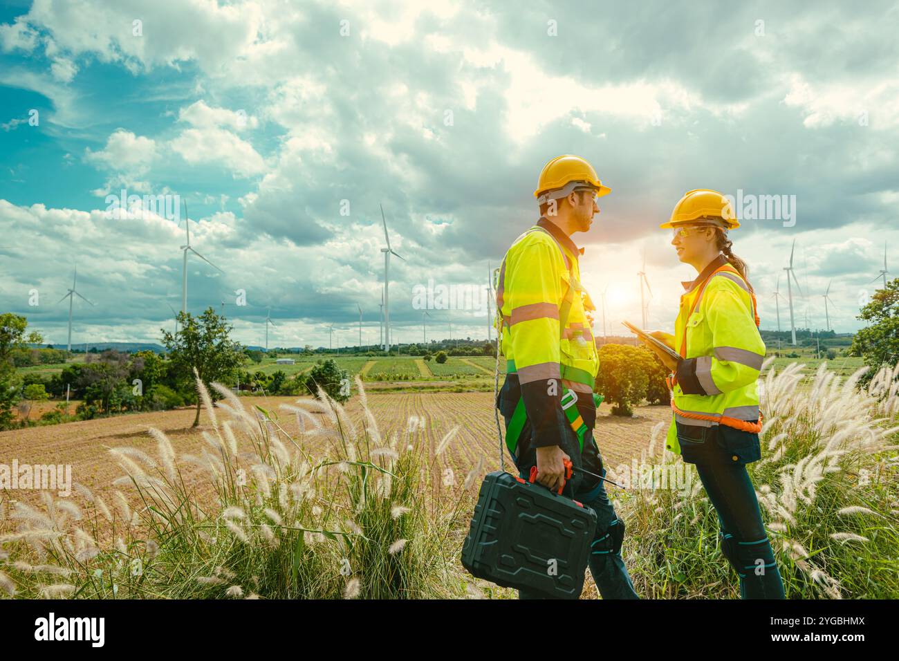 Équipe d'ingénieur homme et femmes ouvriers équipe de service éoliennes travaillant ensemble sur le champ de ferme de générateur d'électricité éolienne. Banque D'Images
