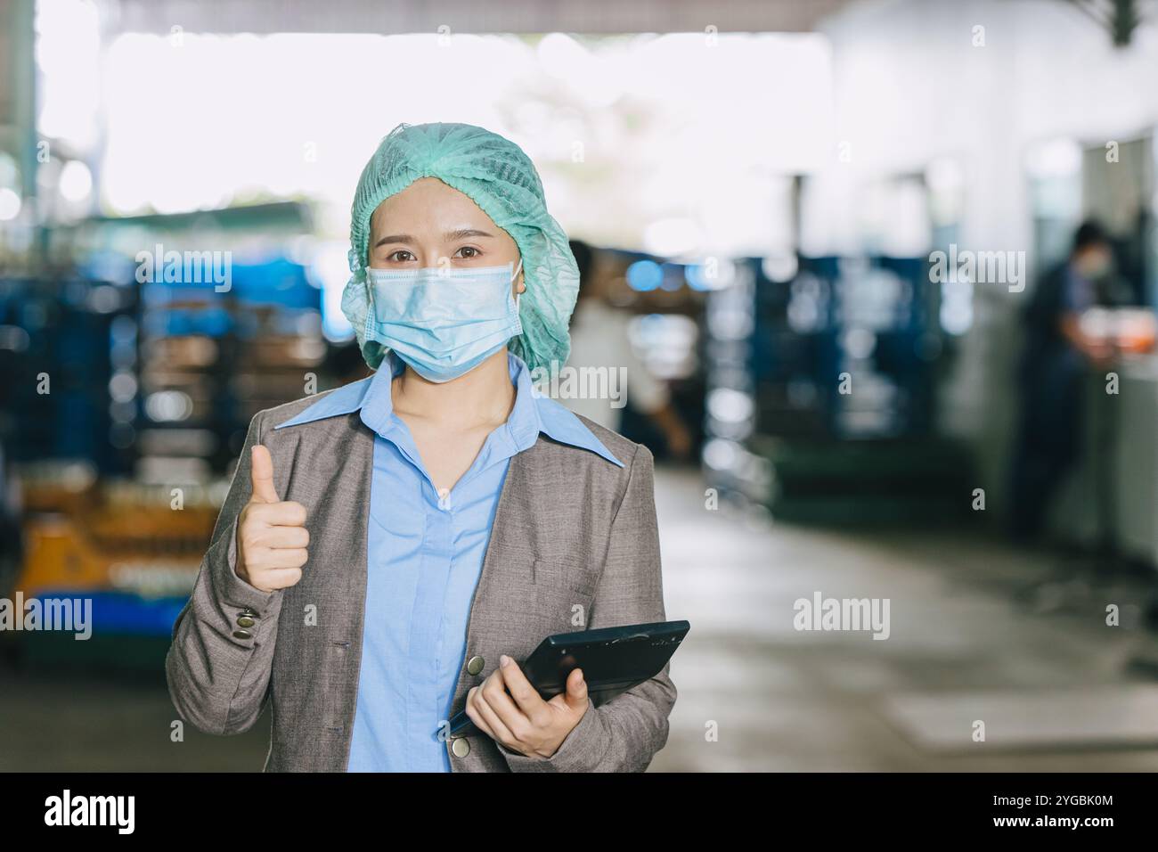 Directeur de l'usine de nourriture et de boissons debout pouces vers le haut, pour une bonne hygiène soins de santé porter contaminer masque protecteur visage et cheveux. Banque D'Images