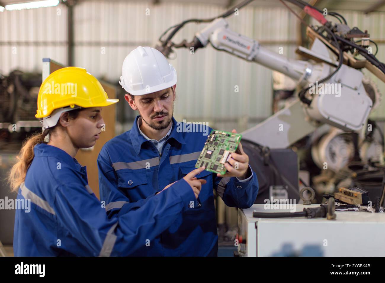 Le service d'équipe de travailleur d'ingénieur heureux remplace la partie cassée du bras de soudure robotique automatique de l'industrie. Machine robot de maintenance de réparation d'équipe de mécanicien dans WO Banque D'Images
