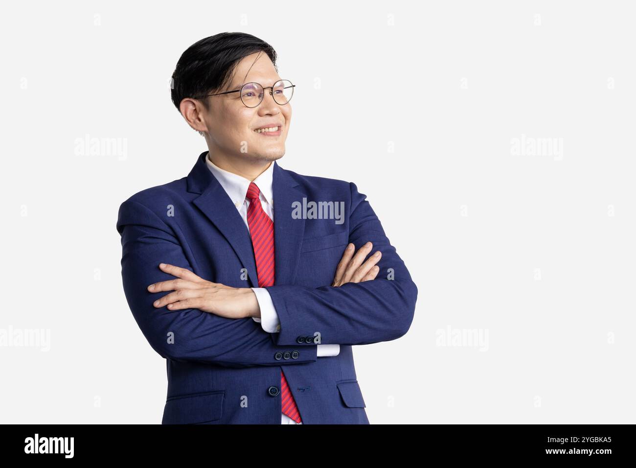Bras confiant asiatique intelligent d'homme d'affaires plié isolé sur fond blanc. Homme heureux dans les croix de bras de costume d'affaires portant des lunettes. Banque D'Images