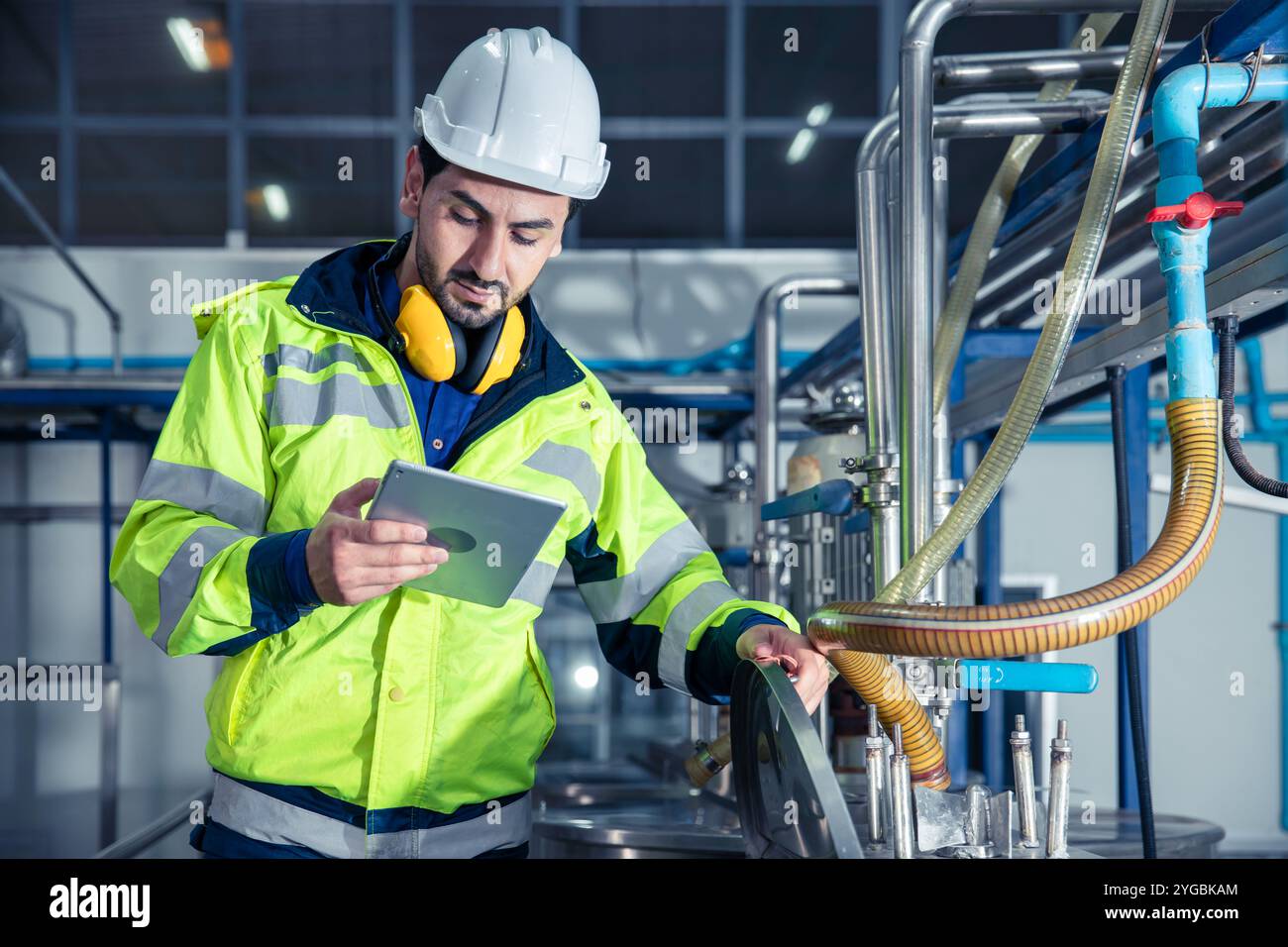 Ouvrier industriel d'usine, personnel d'ingénieur travaillant dans l'usine de nourriture et de boissons, contrôle de l'état de qualité de l'approvisionnement de tuyau liquide dans l'usine. Banque D'Images