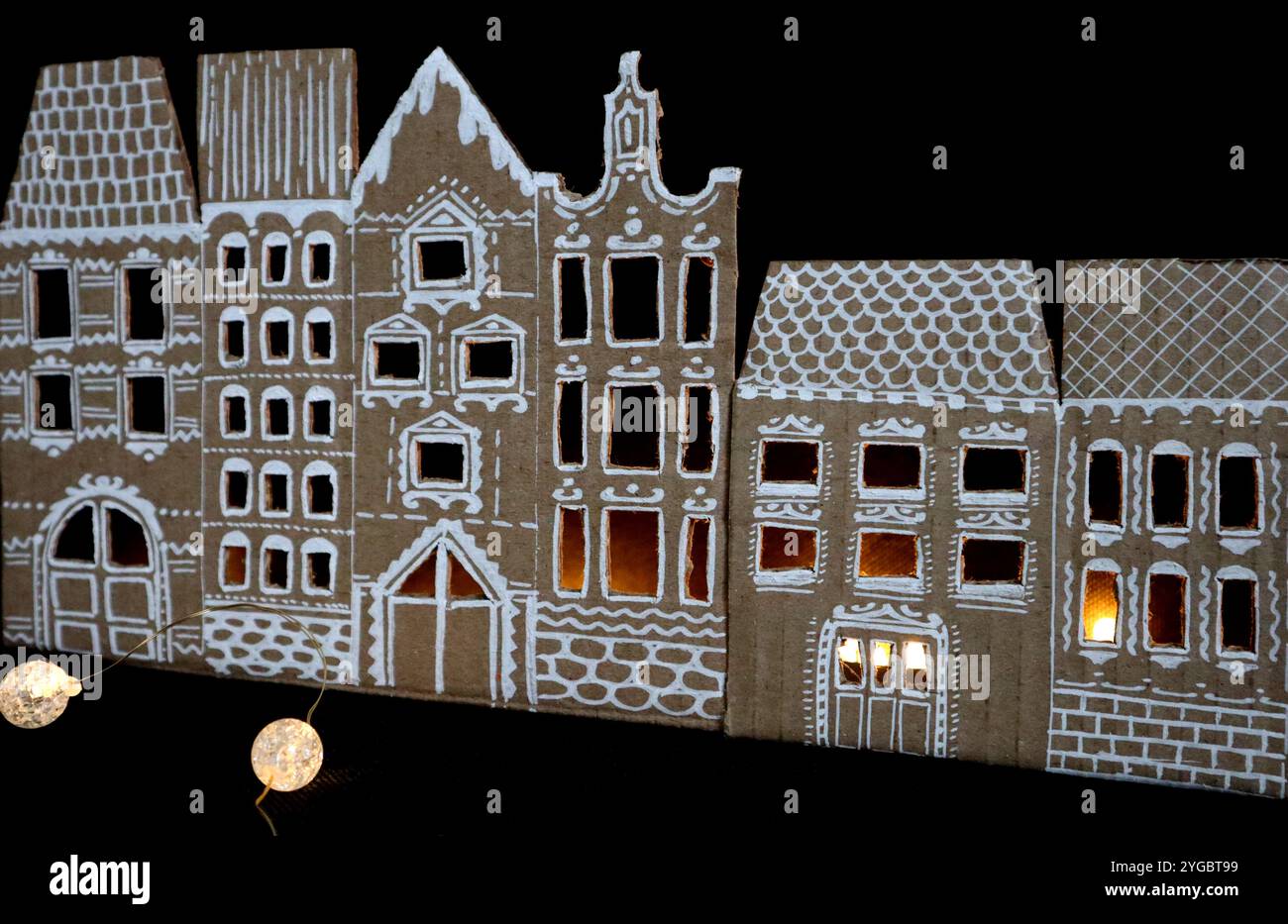 Panorama de vieilles maisons. Fabriqué à la main. Les maisons sont découpées dans du carton. Peint en blanc. Fond noir. Il y a de la lumière dans les fenêtres. Devant le Banque D'Images