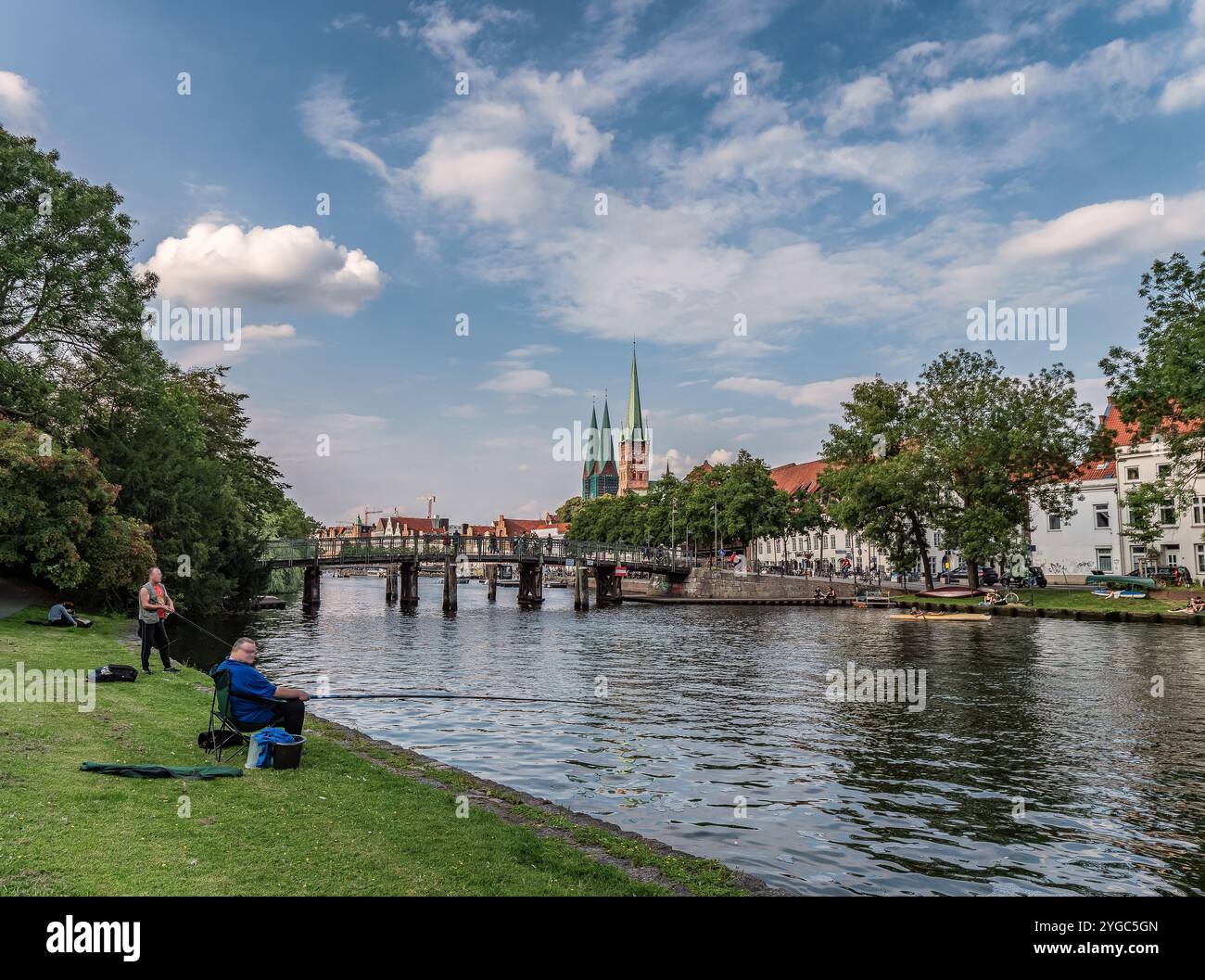 Une vue sereine sur l'architecture européenne historique par une rivière calme, entourée d'une verdure luxuriante. L'image capture la beauté de la nature et le charme urbain und Banque D'Images